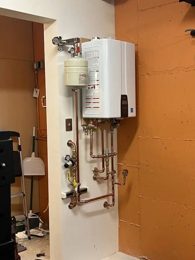 Plumbing technician inspecting water heater connections in Osprey
